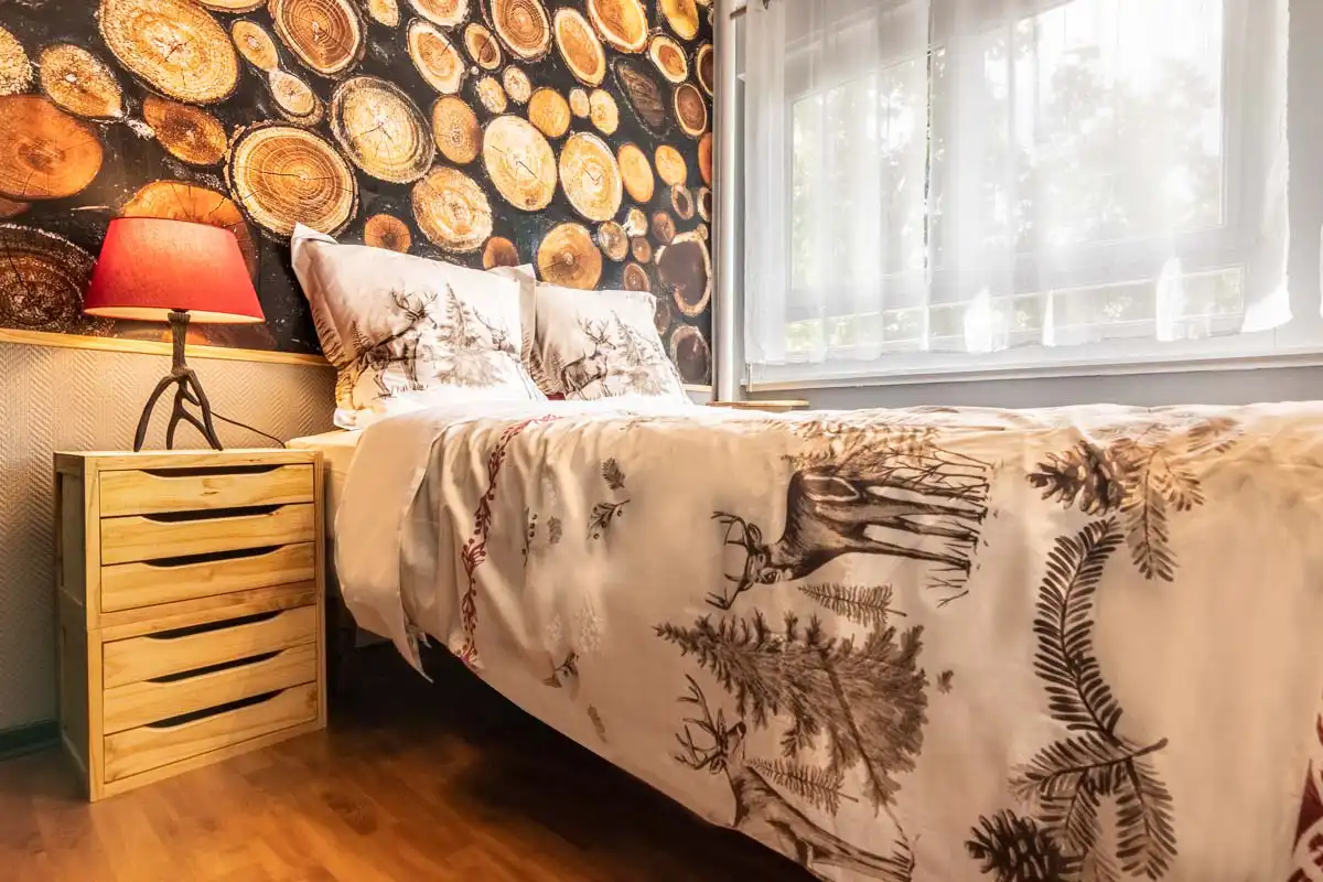 L'ambiance de chalet est omniprésente avec des cerfs, des sapins, un chevet à tiroirs en bois et un papier peint panoramique de rondins.