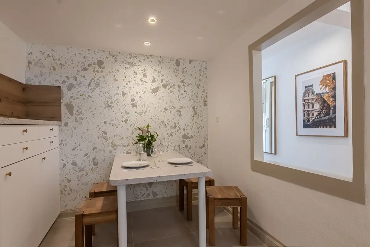 Coin repas de la cuisine avec un papier peint effet terrazzo géant assorti au plan de travail