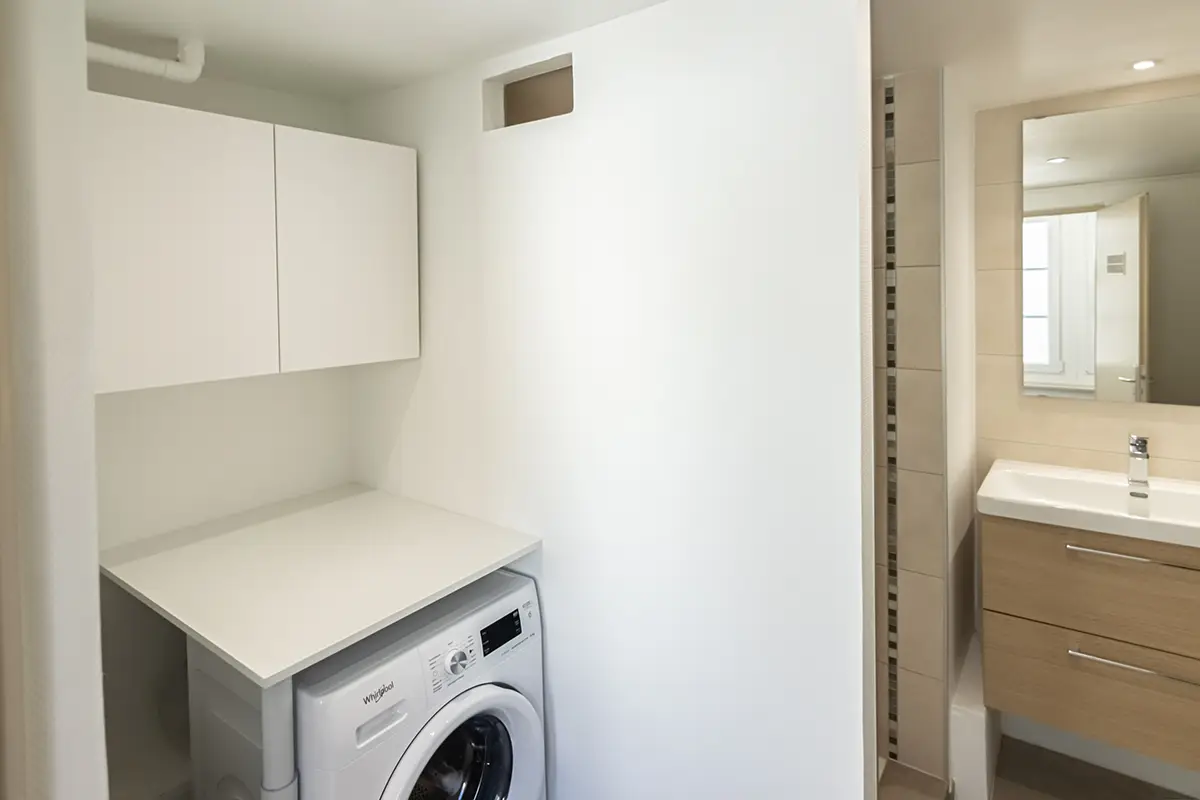 Pièce compartimentée avec lave-linge, douche et vasque.